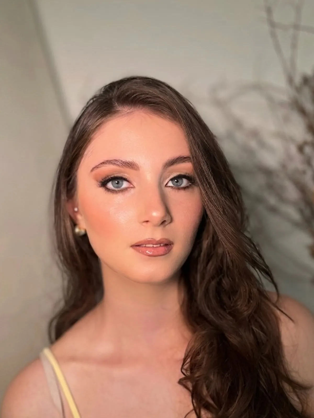 Dieselbe junge Frau mit fertigem Soft-Glam-Make-up und offenen Locken